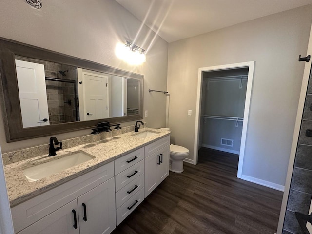 bathroom with tiled shower, hardwood / wood-style floors, vanity, and toilet