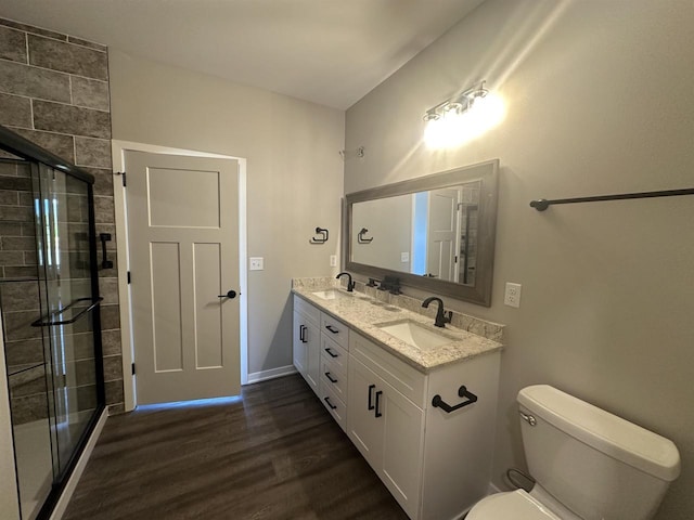 bathroom featuring toilet, vanity, a shower with shower door, and hardwood / wood-style flooring