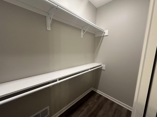 walk in closet with dark wood-type flooring