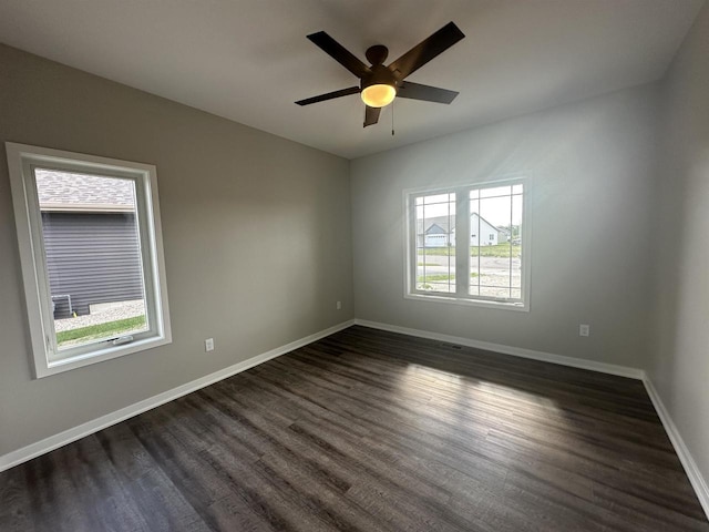 spare room with ceiling fan, a healthy amount of sunlight, and dark hardwood / wood-style floors