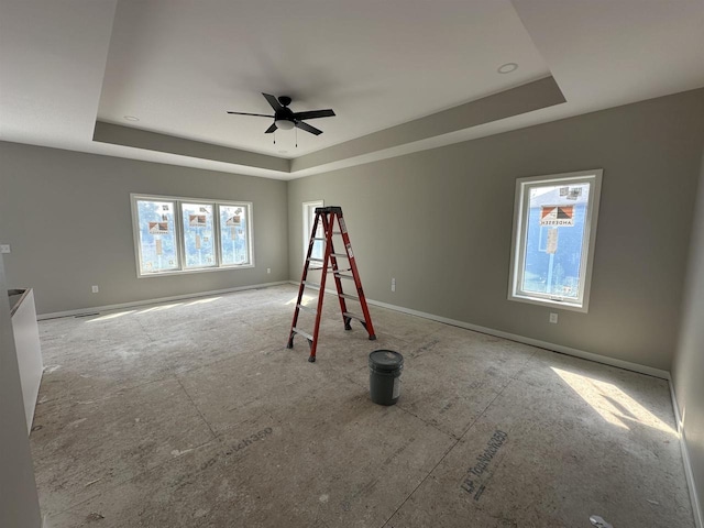 interior space with a raised ceiling and ceiling fan