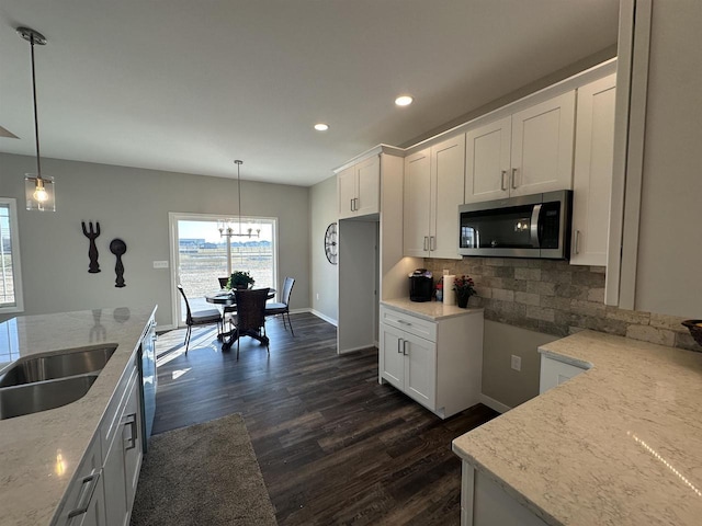 kitchen featuring white cabinetry, light stone countertops, decorative light fixtures, and dark hardwood / wood-style floors