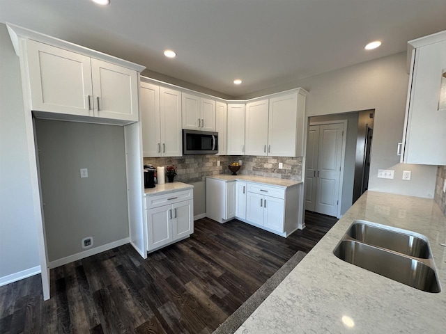 kitchen featuring white cabinets, decorative backsplash, dark hardwood / wood-style flooring, and sink