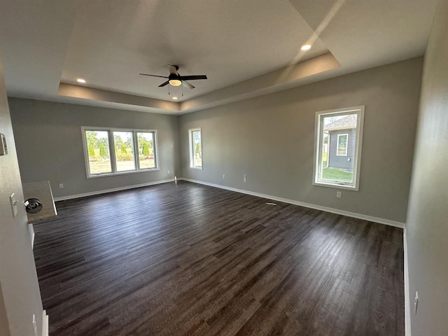 spare room featuring dark hardwood / wood-style flooring, a tray ceiling, and ceiling fan