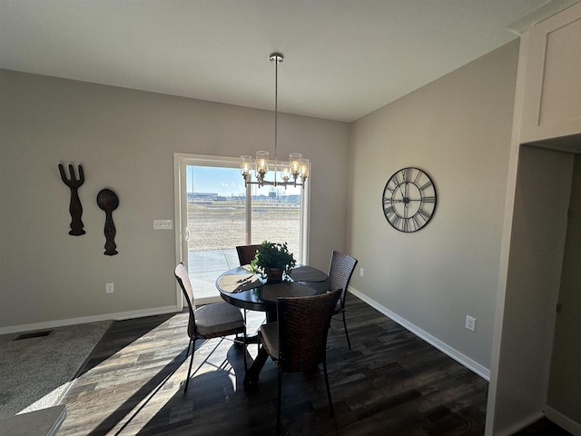 dining area with dark hardwood / wood-style flooring and a chandelier