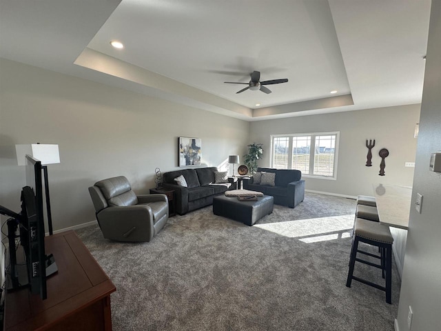 carpeted living room featuring ceiling fan and a tray ceiling