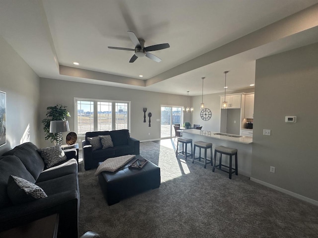 living room with ceiling fan, a raised ceiling, and carpet floors