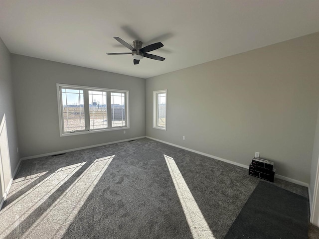 unfurnished room with ceiling fan and dark carpet