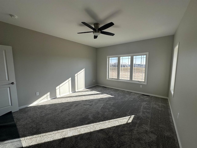 empty room featuring dark carpet and ceiling fan