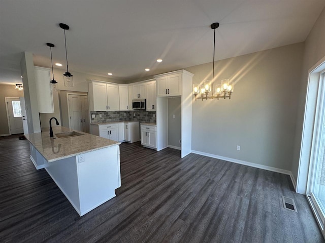 kitchen with kitchen peninsula, sink, white cabinets, and pendant lighting