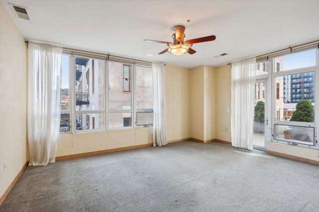 empty room featuring ceiling fan, carpet, and a healthy amount of sunlight