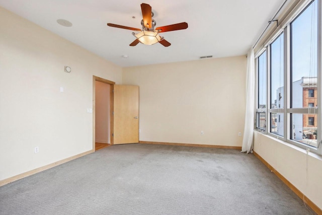 empty room featuring ceiling fan, plenty of natural light, and light colored carpet