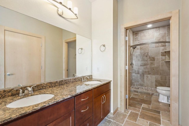 bathroom featuring a tile shower, vanity, and toilet