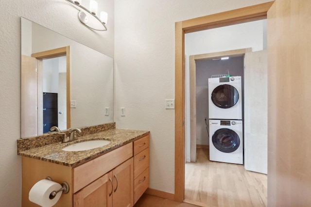 bathroom featuring hardwood / wood-style floors, vanity, and stacked washer / dryer