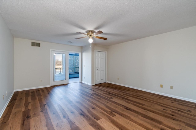 empty room with a textured ceiling, dark hardwood / wood-style flooring, and ceiling fan