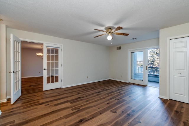 empty room featuring a textured ceiling, dark hardwood / wood-style floors, ceiling fan with notable chandelier, and french doors