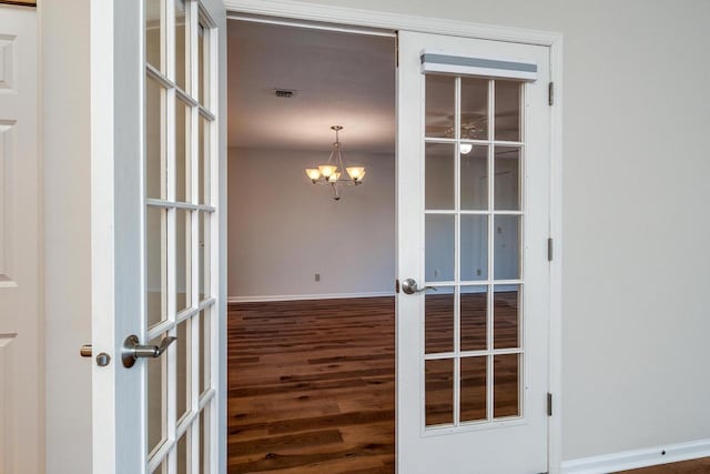 interior space with french doors, dark hardwood / wood-style floors, and a notable chandelier