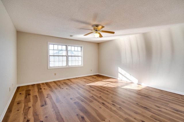 spare room with ceiling fan, a textured ceiling, and hardwood / wood-style flooring