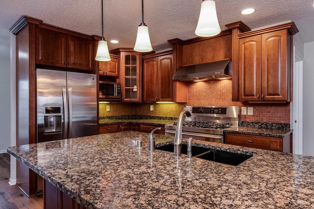 kitchen featuring wall chimney exhaust hood, a textured ceiling, appliances with stainless steel finishes, decorative light fixtures, and dark hardwood / wood-style flooring