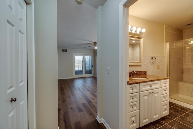 bathroom featuring tiled shower, wood-type flooring, vanity, and ceiling fan