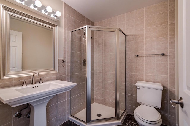 bathroom featuring toilet, tile walls, and a shower with shower door