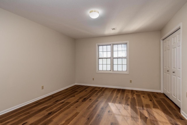 unfurnished bedroom featuring a textured ceiling, a closet, and dark hardwood / wood-style floors