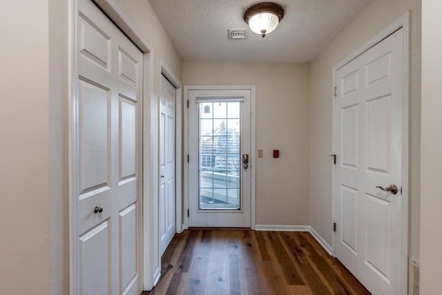 doorway to outside with dark hardwood / wood-style flooring and a textured ceiling