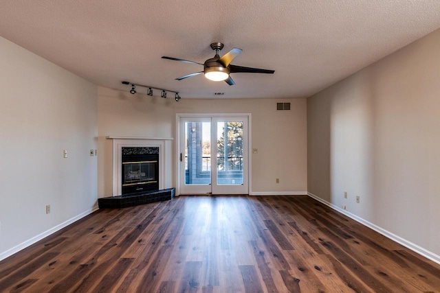 unfurnished living room with a tile fireplace, ceiling fan, dark wood-type flooring, and a textured ceiling