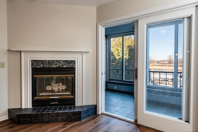 doorway featuring a tile fireplace, wood-type flooring, and a textured ceiling