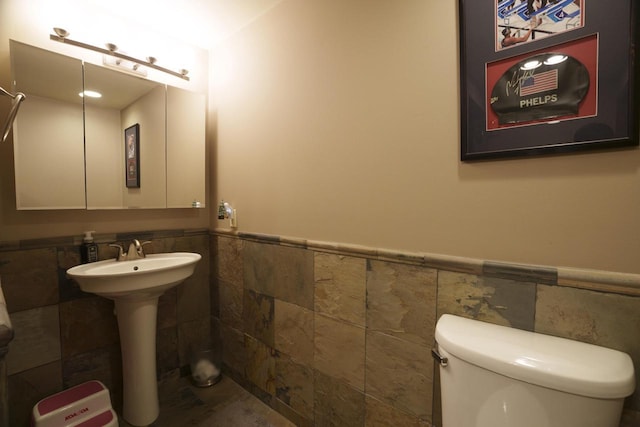 bathroom with toilet, tile walls, and sink