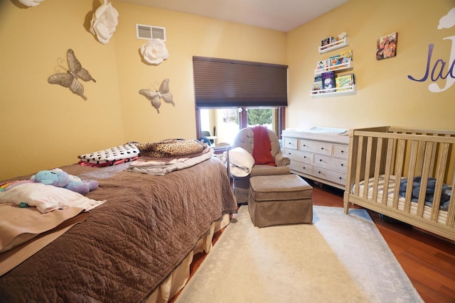 bedroom featuring a crib and wood-type flooring