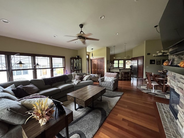 living room featuring ceiling fan, dark hardwood / wood-style floors, plenty of natural light, lofted ceiling, and a fireplace