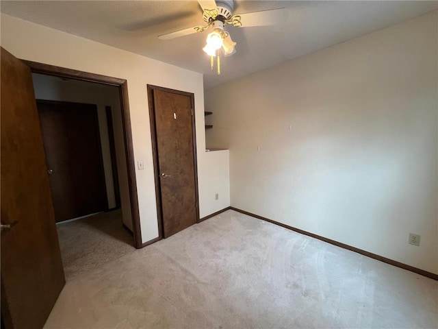 unfurnished bedroom with a closet, light colored carpet, and ceiling fan