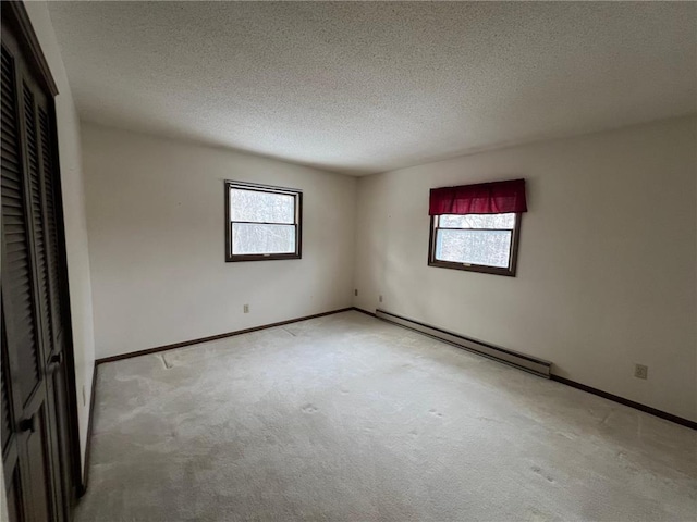 unfurnished bedroom with light carpet, a textured ceiling, and a baseboard radiator