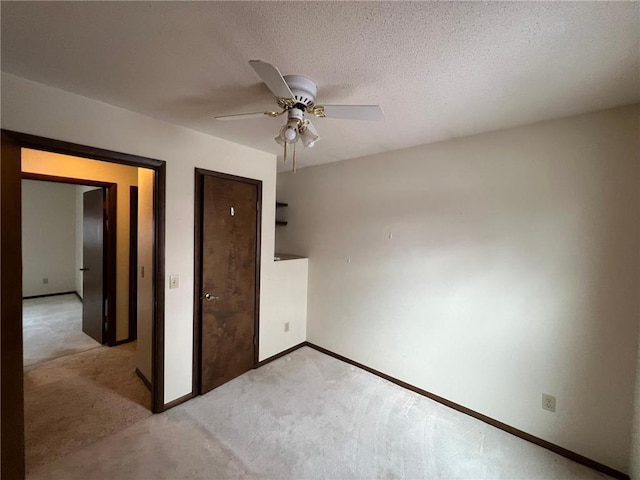 unfurnished bedroom with a textured ceiling, ceiling fan, and light carpet