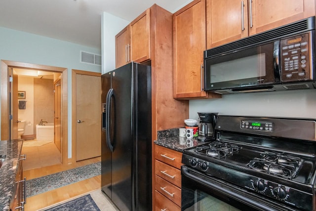 kitchen featuring light tile patterned floors, dark stone countertops, and black appliances