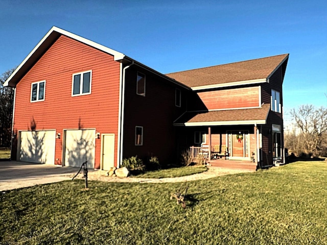 rear view of house featuring covered porch, a yard, and a garage