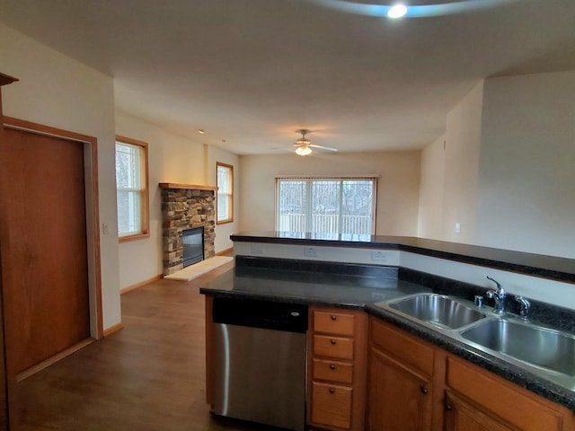 kitchen featuring ceiling fan, dishwasher, sink, hardwood / wood-style floors, and a fireplace