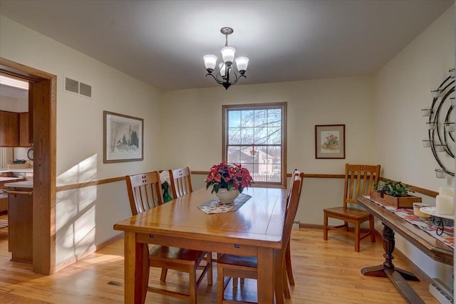 dining area featuring an inviting chandelier and light hardwood / wood-style flooring