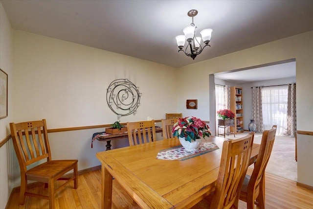 dining area with light hardwood / wood-style floors and an inviting chandelier