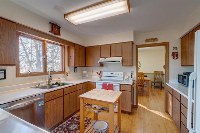 kitchen with appliances with stainless steel finishes, light hardwood / wood-style floors, and sink