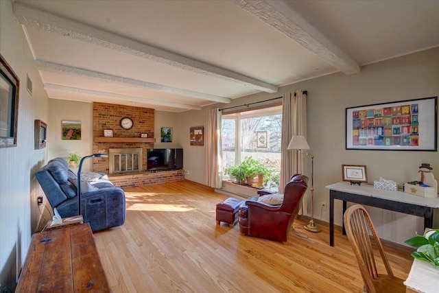 living room featuring beamed ceiling, wood-type flooring, and a fireplace