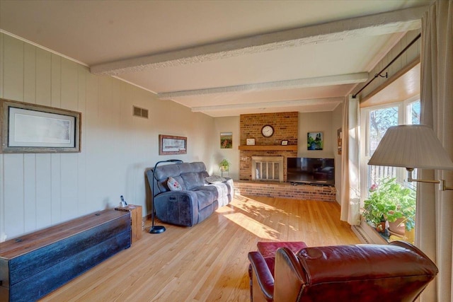 living room featuring hardwood / wood-style floors, beam ceiling, and a fireplace