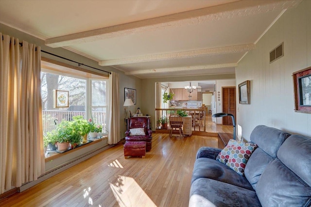 living room with beamed ceiling, light hardwood / wood-style floors, and an inviting chandelier