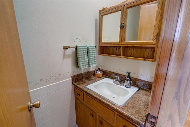 bathroom featuring vanity and tile walls