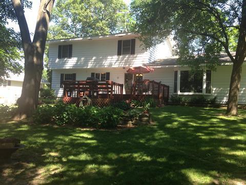 back of property featuring a wooden deck and a lawn