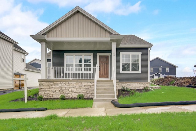 view of front facade with covered porch, a front lawn, board and batten siding, and a shingled roof