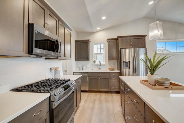 kitchen with stainless steel appliances, a sink, light wood-style floors, light countertops, and pendant lighting