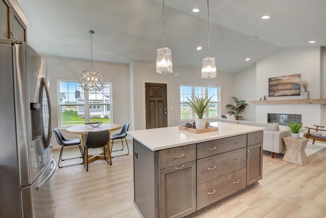 kitchen with hanging light fixtures, stainless steel fridge, light countertops, and open floor plan