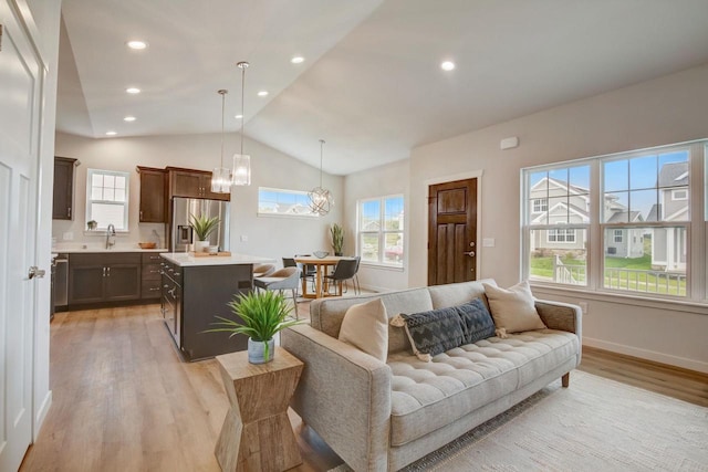 living room featuring a notable chandelier, light hardwood / wood-style floors, and vaulted ceiling